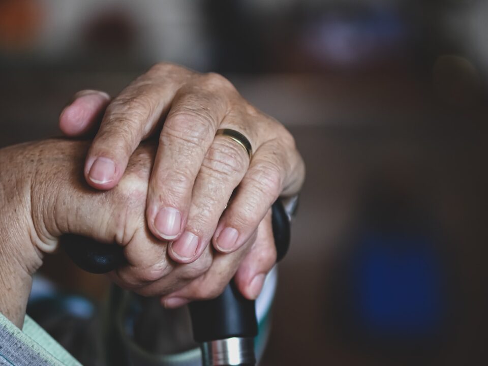 Elderly hands holding cane