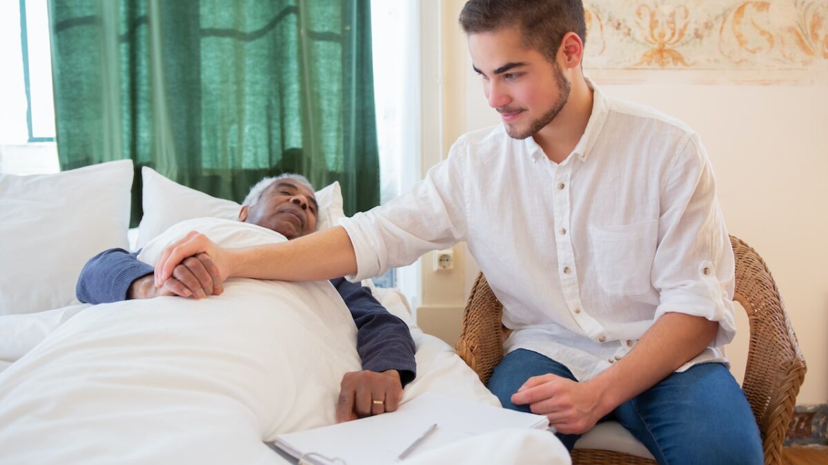 Nurse holding elderly man's hands