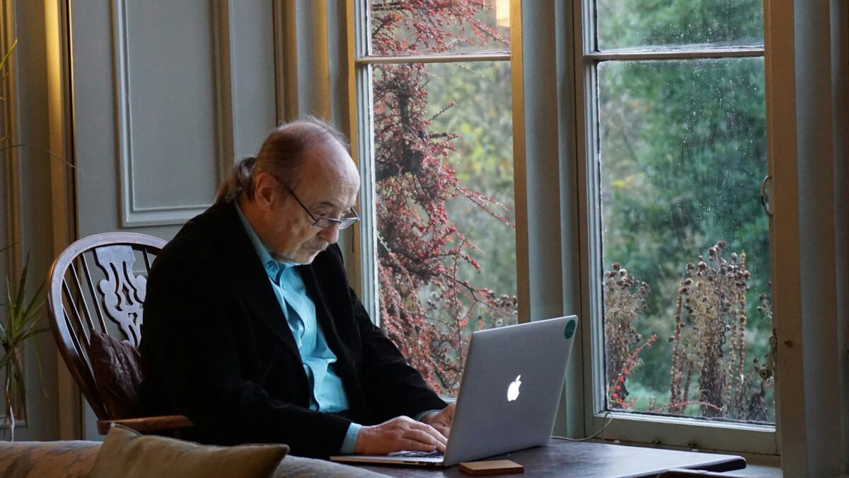 A man sitting in a chair with a laptop computer, focused on the screen