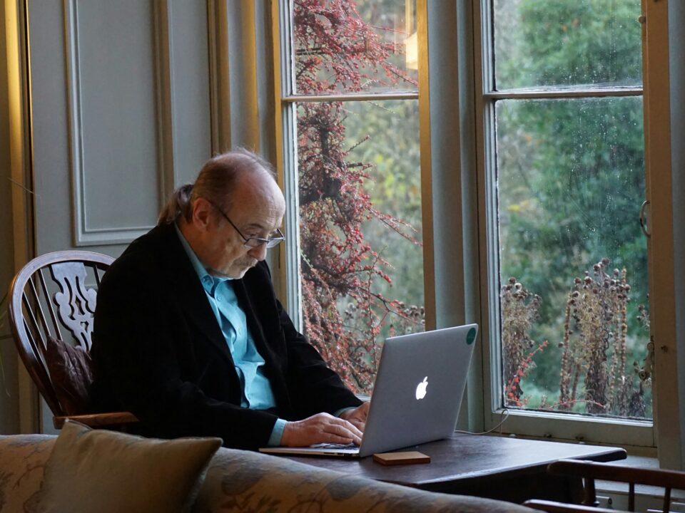 A man sitting in a chair with a laptop computer, focused on the screen