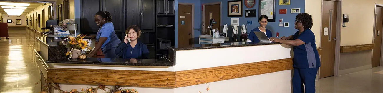 Outside Adam Farms living building with a white picket fence surrounded by green trees in the yard.